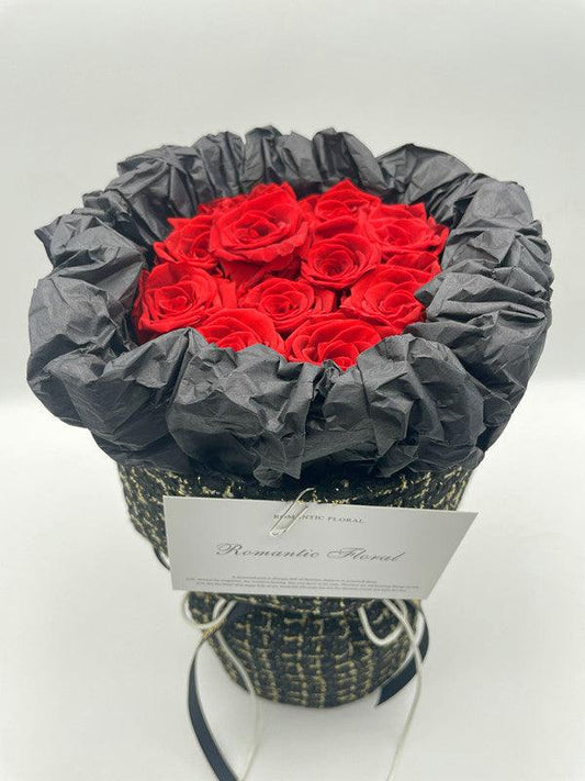 Stunning eternal flowers bouquet with red roses wrapped in black fabric.