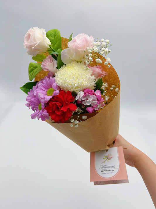 A bouquet of mixed fresh flowers including roses and daisies, wrapped in kraft paper, with 'Flowers Express Co' tag, made in Melbourne.