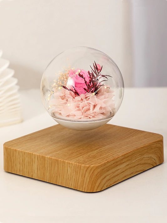 A glass dome with a wooden base, filled with preserved flowers for delivery in Melbourne by Flowers Express Co. The dome is filled with pink and white flowers, with a few red and purple accents.
