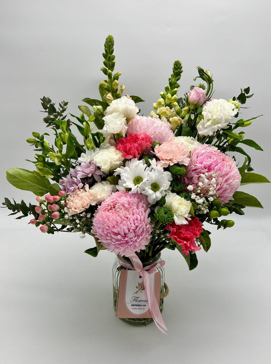 A large bouquet of fresh flowers in shades of pink and white, handcrafted in Melbourne by Flowers Express Co florists and presented in bottles.