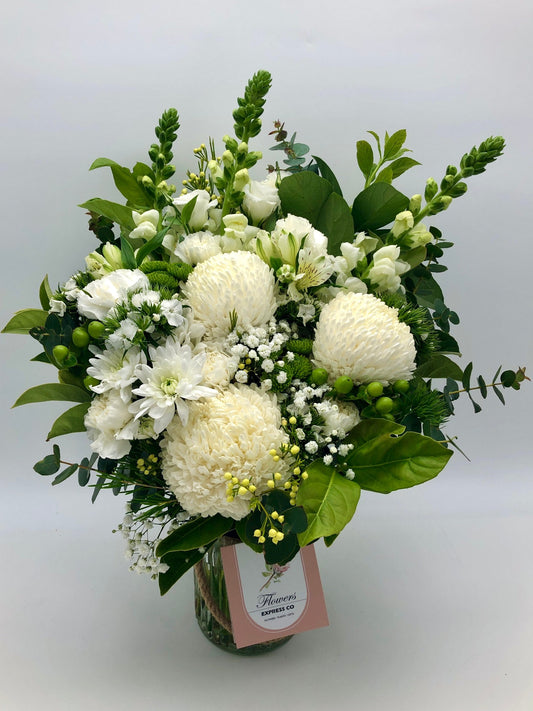 A bouquet of white disbuds mums in a bottle, made by a florist at Flowers Express Co in Melbourne.