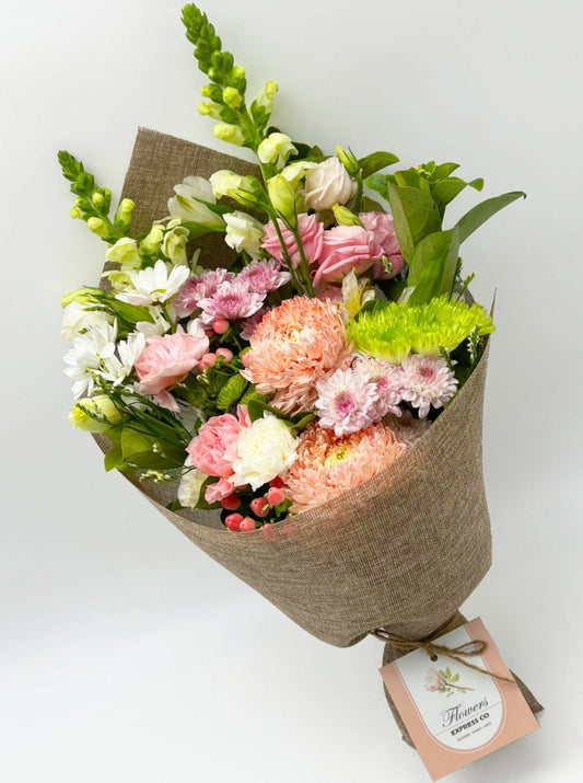 A bouquet of pink and white flowers wrapped in a piece of jute, set against a white background, by Flowers Express Co florists in Melbourne.