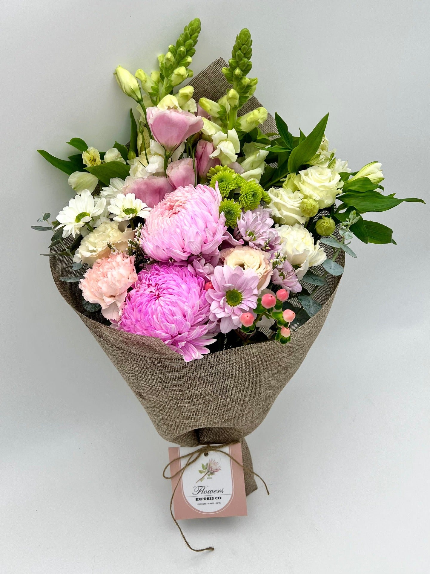 Medium pink and white mixed flowers wrapped in a hessian-feel mesh against a white wall background. Great for gifting and decorating, available for delivery in Melbourne, VIC.