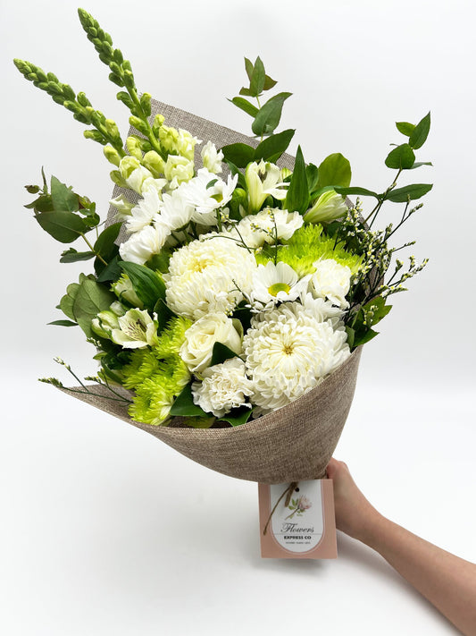 A bouquet of white flowers held in hand against a white background, wrapped by jute and made by a florist in Melbourne.