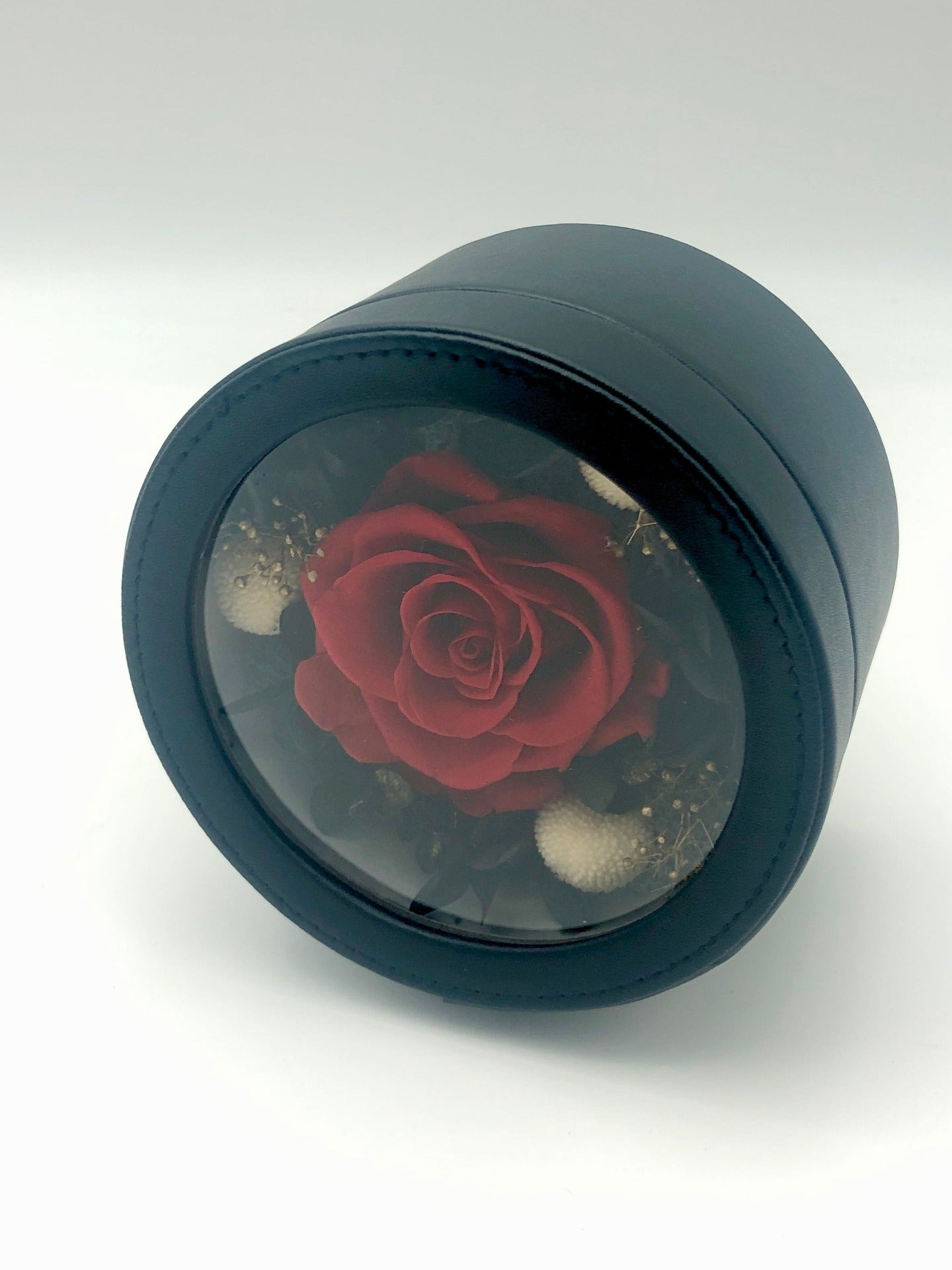 A photo of a stunning preserved red rose, all beautifully presented in a black gift box with a clear lid. A perfect gift for any special occasion.