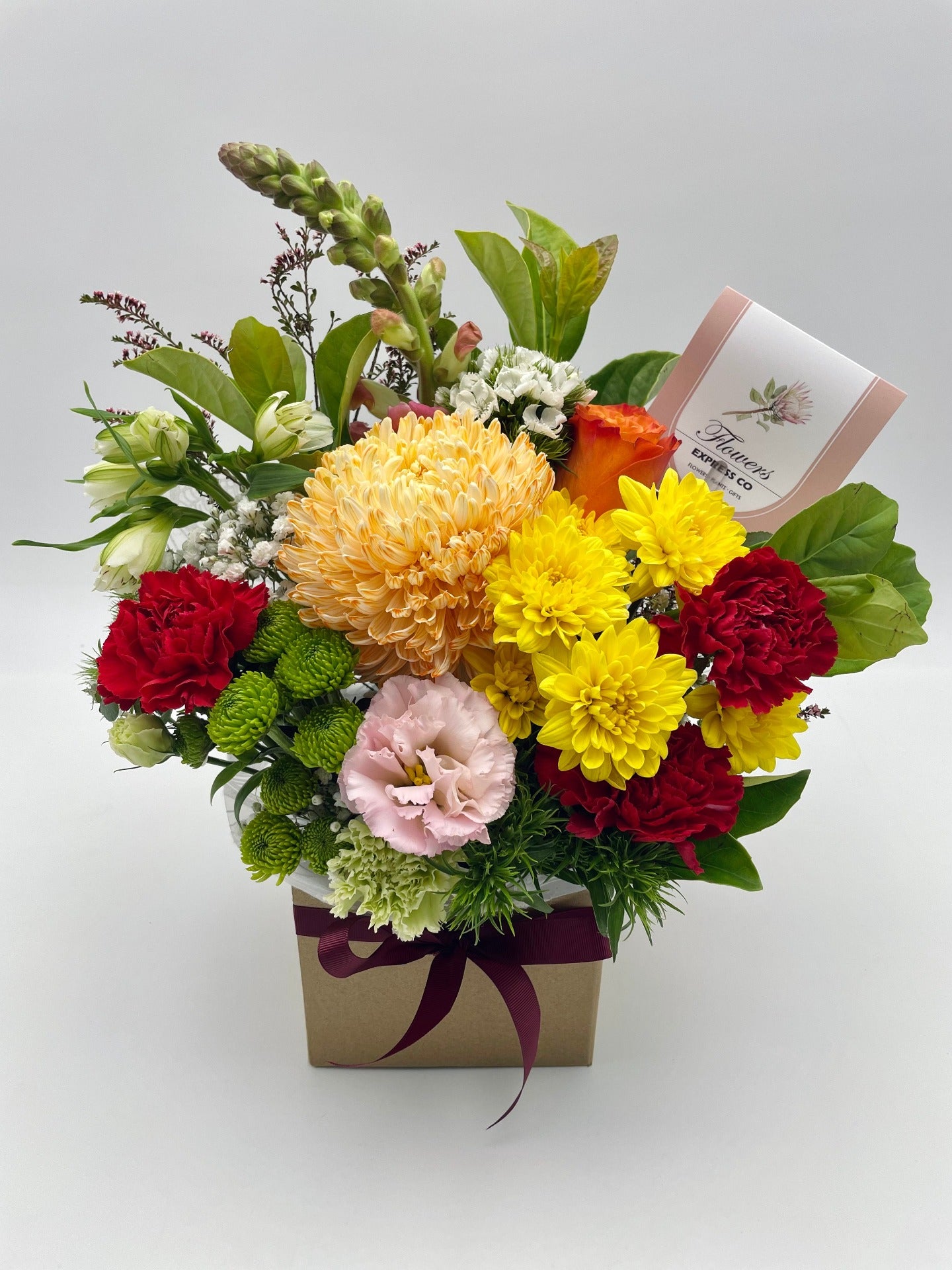A bouquet of red and orange flowers in a brown carton, made by a florist at Flowers Express Co in Melbourne.