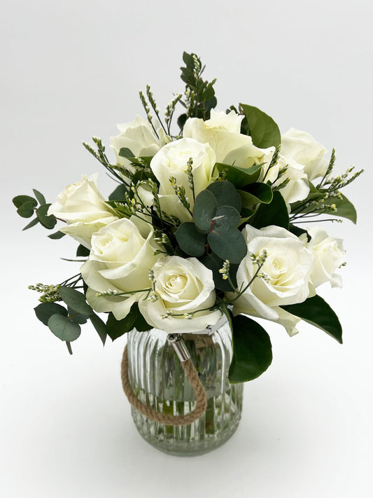 A florist in Melbourne arranged ten white roses and other filler flowers in a glass vase