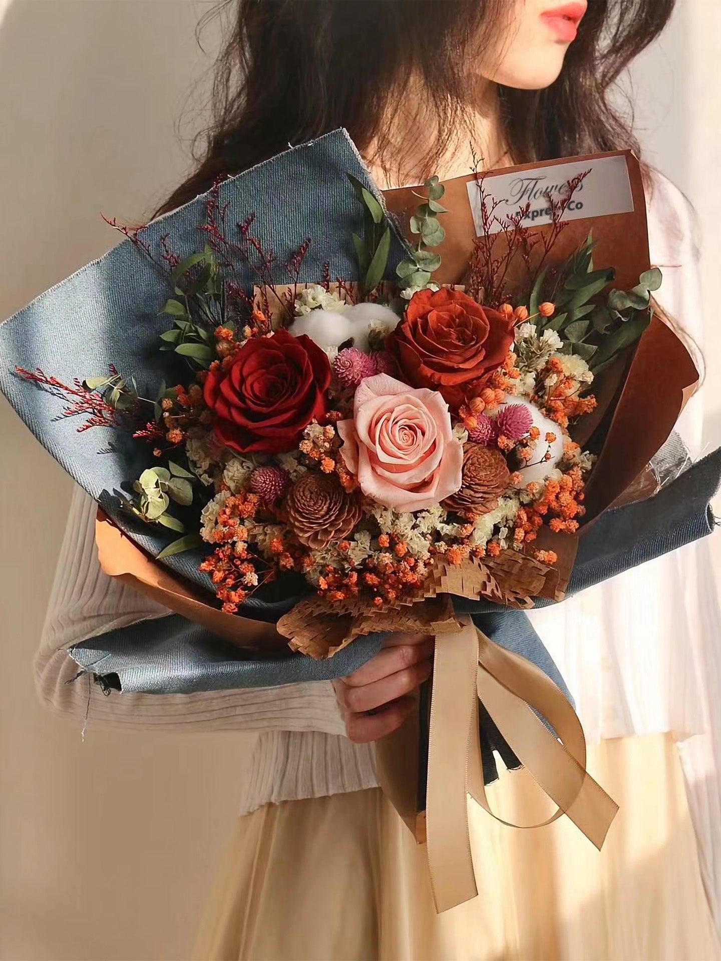 A girl holding a bouquet of preserved roses. The roses are wrapped in a mix of denim and kraft paper. Handmade by Flowers Express Co florist in Melbourne.