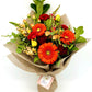 Vibrant orange and red bouquet with gerberas, roses, and lush green foliage