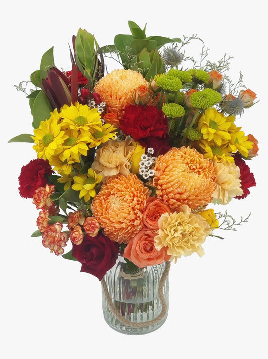 A large floral bouquet of orange and red toned flowers handcrafted in Melbourne by Flowers Express Co florists and presented in jar.