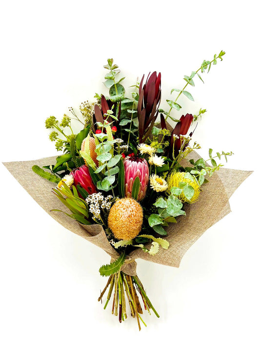 A stunning bouquet of native flowers in beautiful shades of red, yellow, and orange, perfect for brightening up any room!