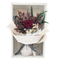 Red preserved rose and dried flowers in beige wrapping paper with grey ribbon, elegantly arranged in a white box.