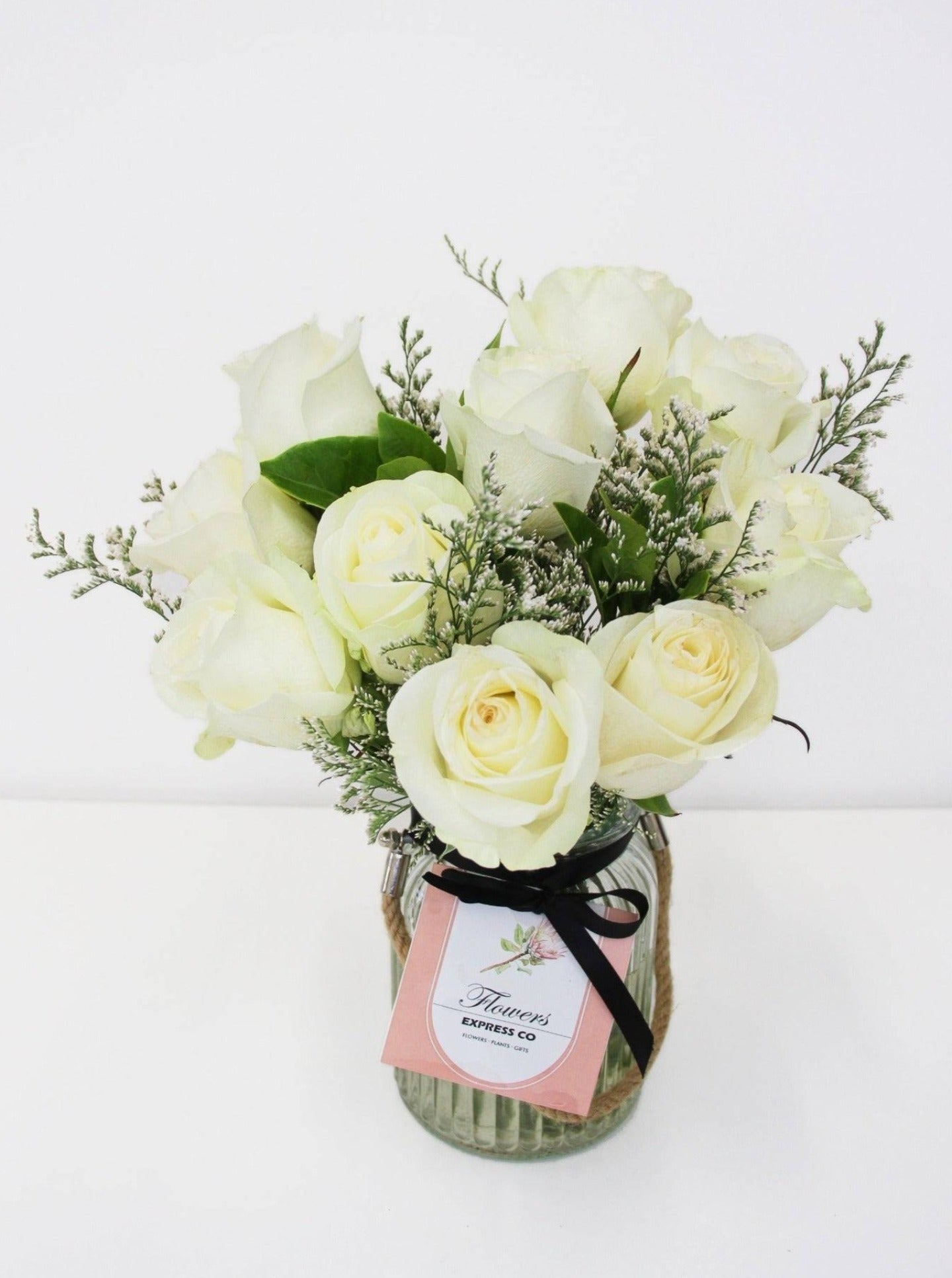 Ten stems of white roses are arranged in a glass jar made by a florist in Melbourne.